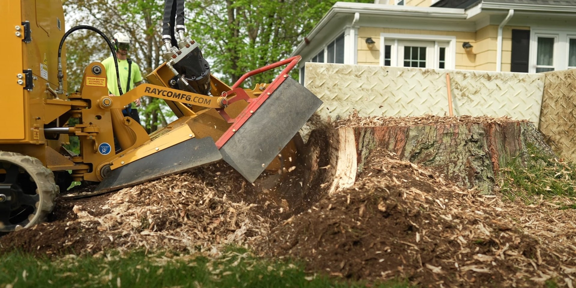 Professional stump grinding service in residential backyard Industrial stump grinder removing tree stump from residential yard